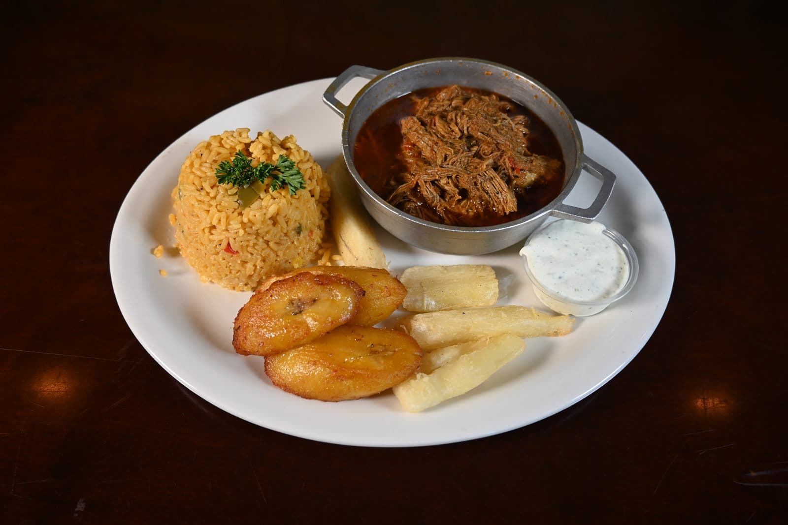 Ropa vieja served in a traditional Cuban caldero with yellow rice, tostones and yuca
