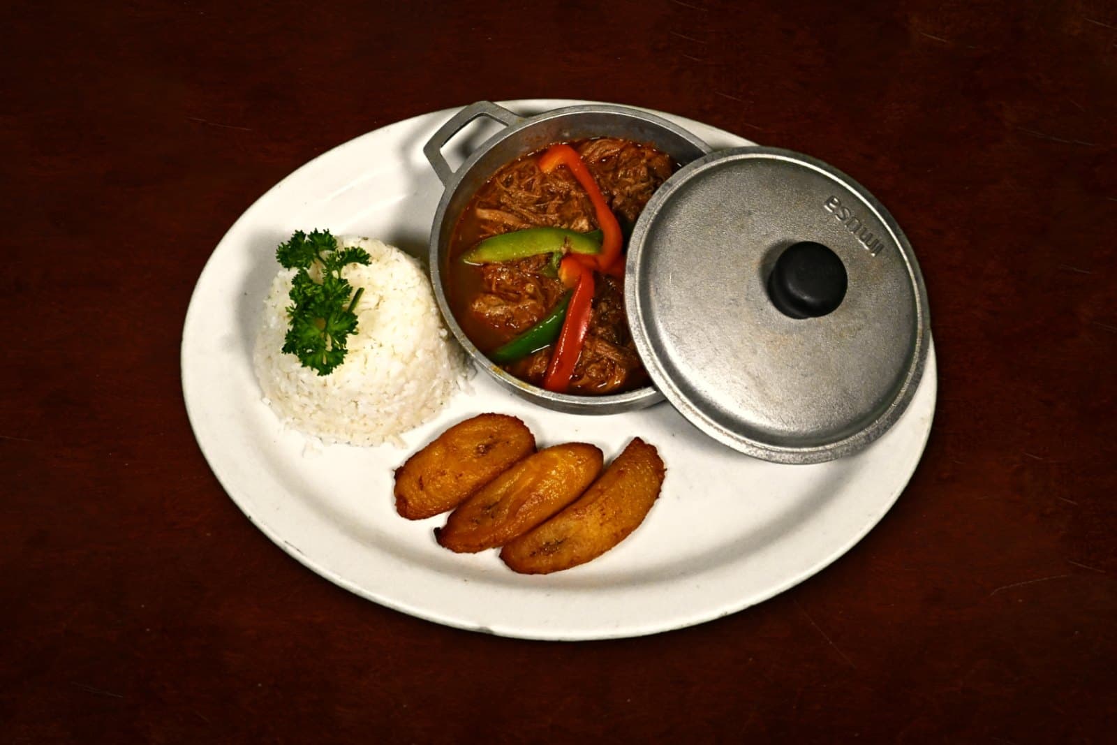 Ropa Vieja: slow-roasted in creole sauce, white rice, maduros, plated on a dark wood table